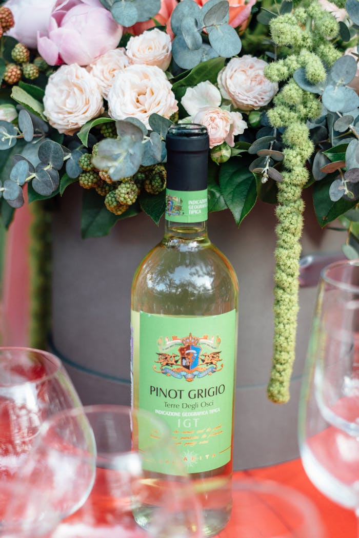A bottle of Pinot Grigio wine alongside an elegant floral arrangement, showcasing luxury and refinement.